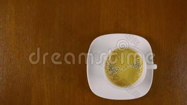 顶景特写男人的手拿着白色的咖啡，喝了它，放在棕色的木桌上。 空间